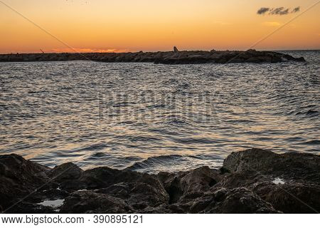 View Of The Sea And Stones On The Pedregalejo Beach At Dusk.