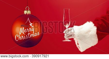 Hand Of Santa Claus Holding Glass, Greeting With New Year 2021 And Christmas. Red Background With Le