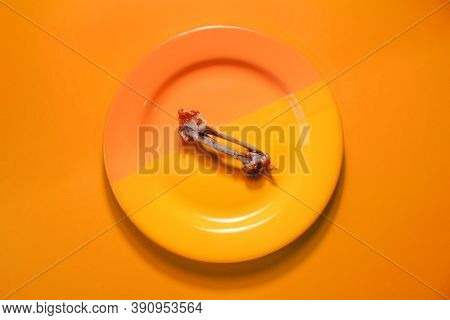 Chicken Bones On A Plate, Top View. Gnawed Bones, Diet, Weight Loss Concept. Bright Orange Backgroun
