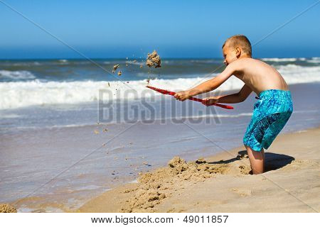 Boy Digging A Hole At The Beach