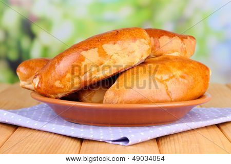 Empanadillas al horno frescos, en mesa de madera, sobre fondo brillante