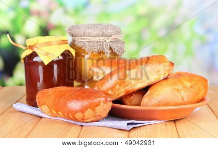 Empanadillas al horno frescos con mermelada de frutas, en la mesa de madera, sobre fondo brillante