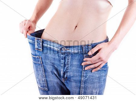 여자는 오래 된 청바지를 입고 그녀의 체중 감량을 보여줍니다.