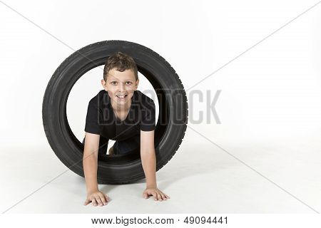 Young boy is climbing through a tire