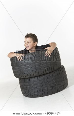 Happy boy is hiding in a fortress made of old tires