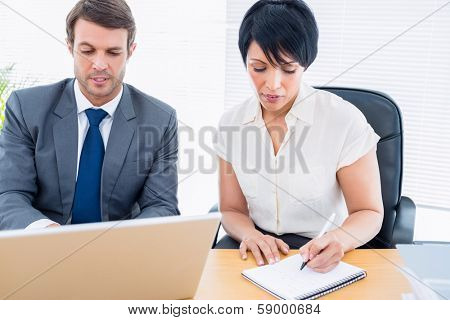 Smartly dressed young man and woman in a business meeting at office desk