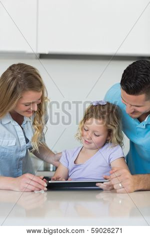 Parents assisting daughter in using tablet computer at table