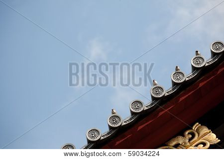 Bird On Japanese Temple Roof Against Blue Sky.