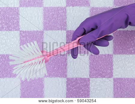 Toilet brush in hand on tile wall background