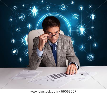 Young businessman sitting at desc with social network icons