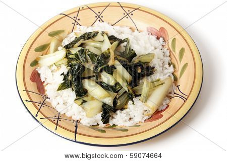 A plate with bok choi asian cabbage chopped and sauteed with sesame oil and soy sauce, served on a bed of white jasmine rice