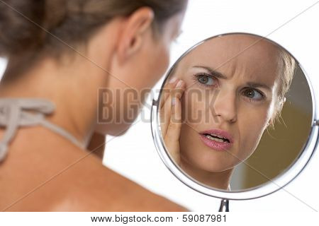Concerned Young Woman Looking In Mirror