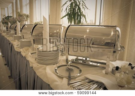 Table with dishware and shiny marmites waiting for guests