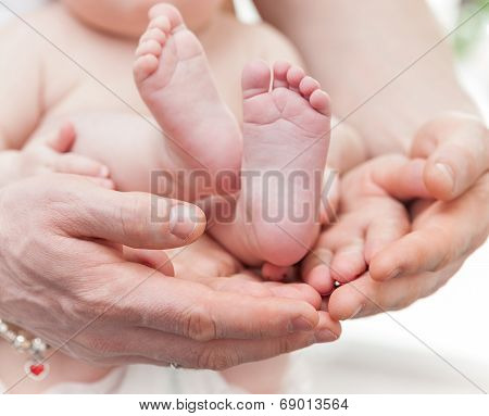 Mother And Father Gently Hold Baby Legs In Hands
