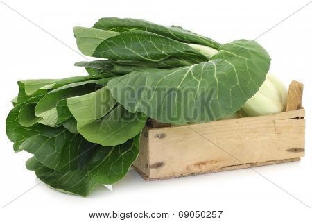 fresh chinese paksoi in a wooden crate on a white background