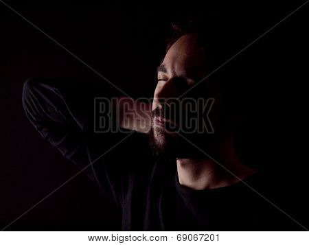 Low Key Image Of A Bearded Man With A Sore Neck