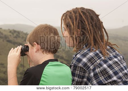 two youth looking for wildlife at a lookout point in the mountains.