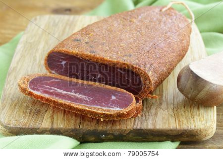 cured meat - basturma in hot pepper (paprika) on a cutting board