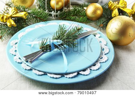 Christmas table setting in blue, golden and whitec olors on grey tablecloth background