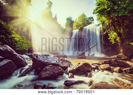Vintage retro effect filtered hipster style image of tropical waterfall with sun rays in Cambodia