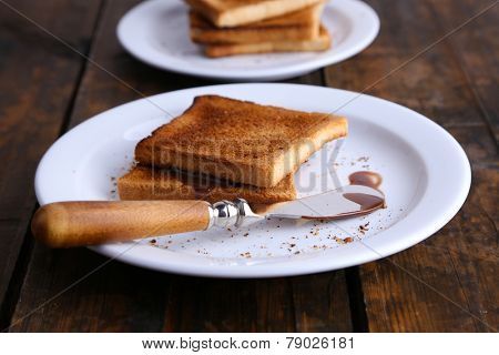Toast bread with chocolate on plate with knife on wooden table background
