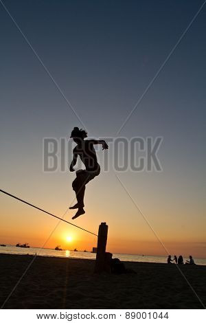 Silhouette of young man balancing on slackline at a beach in Manabi, Ecuador