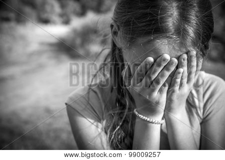 Grunge close-up portrait of a girl crying and covering her face 