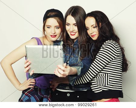 Three girls friends taking selfie with digital tablet, studio shot over gray vackground