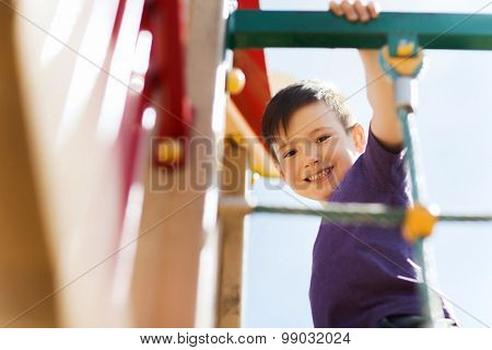 summer, childhood, leisure and people concept - happy little boy on children playground climbing frame