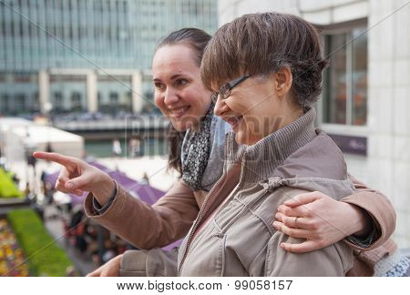 Outdoor family portrait of pension age Mother and her daughter in the city, smiling and looking arou