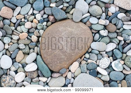Bacground made of pebbles on the beach with one big pebble in the centre