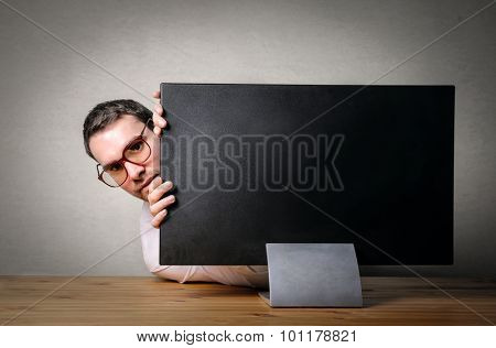 Scared businessman hiding behind a pc