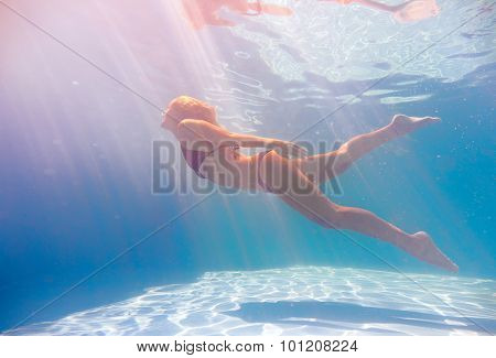 Young woman swimming undewater in the swimming pool