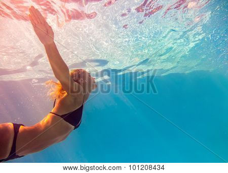 Young woman swimming undewater in the swimming pool
