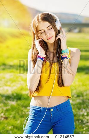 Teenage girl listening to music outdoors in summer
