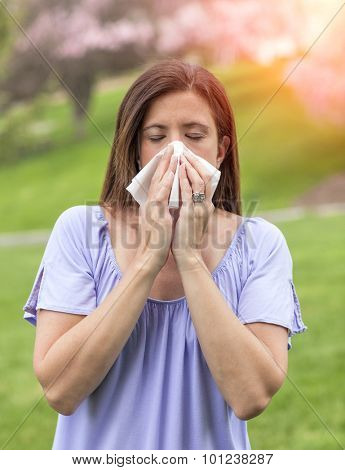 Woman outside blowing nose with a tissue
