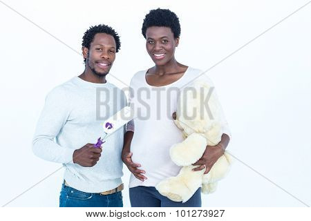 Portrait of woman holding teddy bear while man holding paint roller standing against white backgroubd