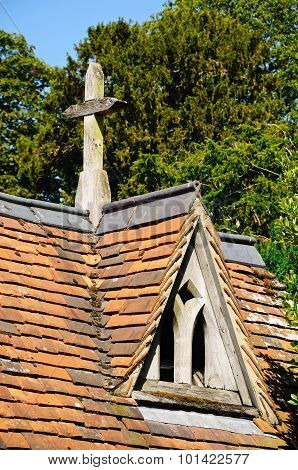 Dormer window in roof with stone cross.