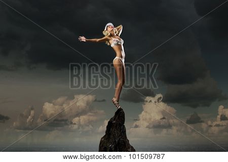 Hot young dancing woman in white bikini on dark background