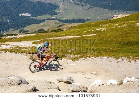 Unidentified biker climbs the hill in Bucegi Mountains in Romania