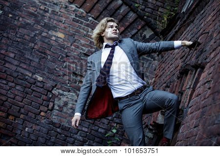 Businessman warrior. Young man  with  war paint on his face climbs up the wall , concept