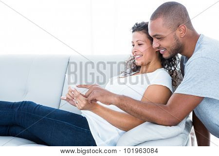 Happy couple looking at sonography relaxing on sofa at home