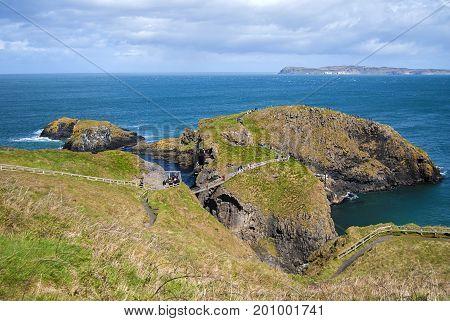 Ballintoy, United Kingdom - May 2, 2016: Carrick-a-Rede Rope Bridge, a popular tourist destination in Northern Ireland. Tourists passing the bridge.