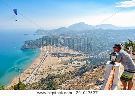 FALIRAKI, RHODES - AUGUST: Man is looking at Tsampika bay from balcony on Rhodes island, Greece