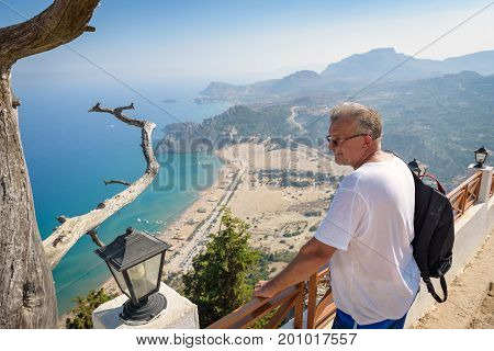TSAMPIKA, RHODES - AUGUST 2017: Man is looking at Tsampika bay from balcony on Rhodes island, Greece