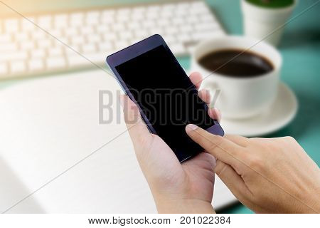 Man Hand Holding Smart Phone With White Blank Empty Screen On Blue Desk Table.