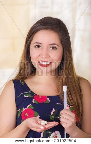 Close up of a young smiling woman holding in her hand a medical object used for vaginal infection medicine and holding in her other hand a soft gelatin vaginal tablet or suppository, treatment of diseases of the reproductive organs of women in a blurred b