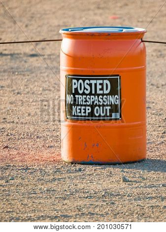An orange barrel with suspended cable used to provide a warning and containment.