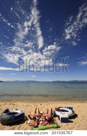 Two caucasian girls relaxing on the beach of Lake Tahoe, with their swimming gears.