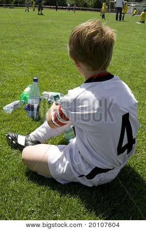 exausted boy takes a rest in the halftime of a football match